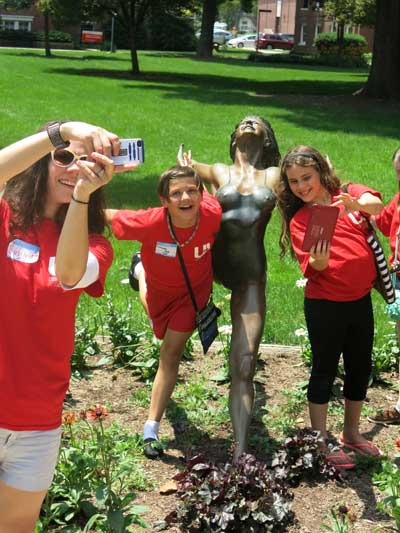 Girls posing next to a ballerina statue
