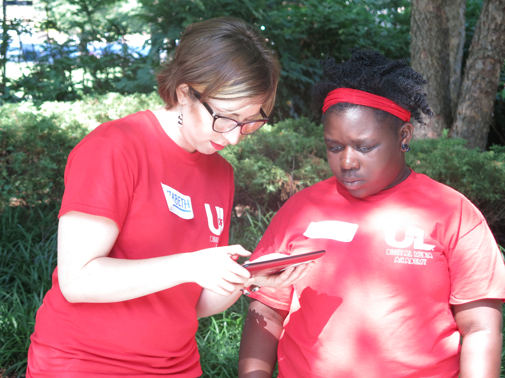 Elizabeth works with a camper on a tablet