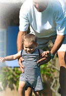 man teaching and playing with child how to walk