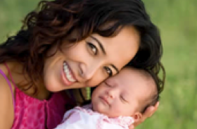 single mother who seems to be pictured in a park because of the grass in the background.