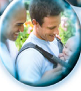 lgbtq family in more natural context--there is a reference to nature because the couple is featured in front of trees. they are probably in a park.